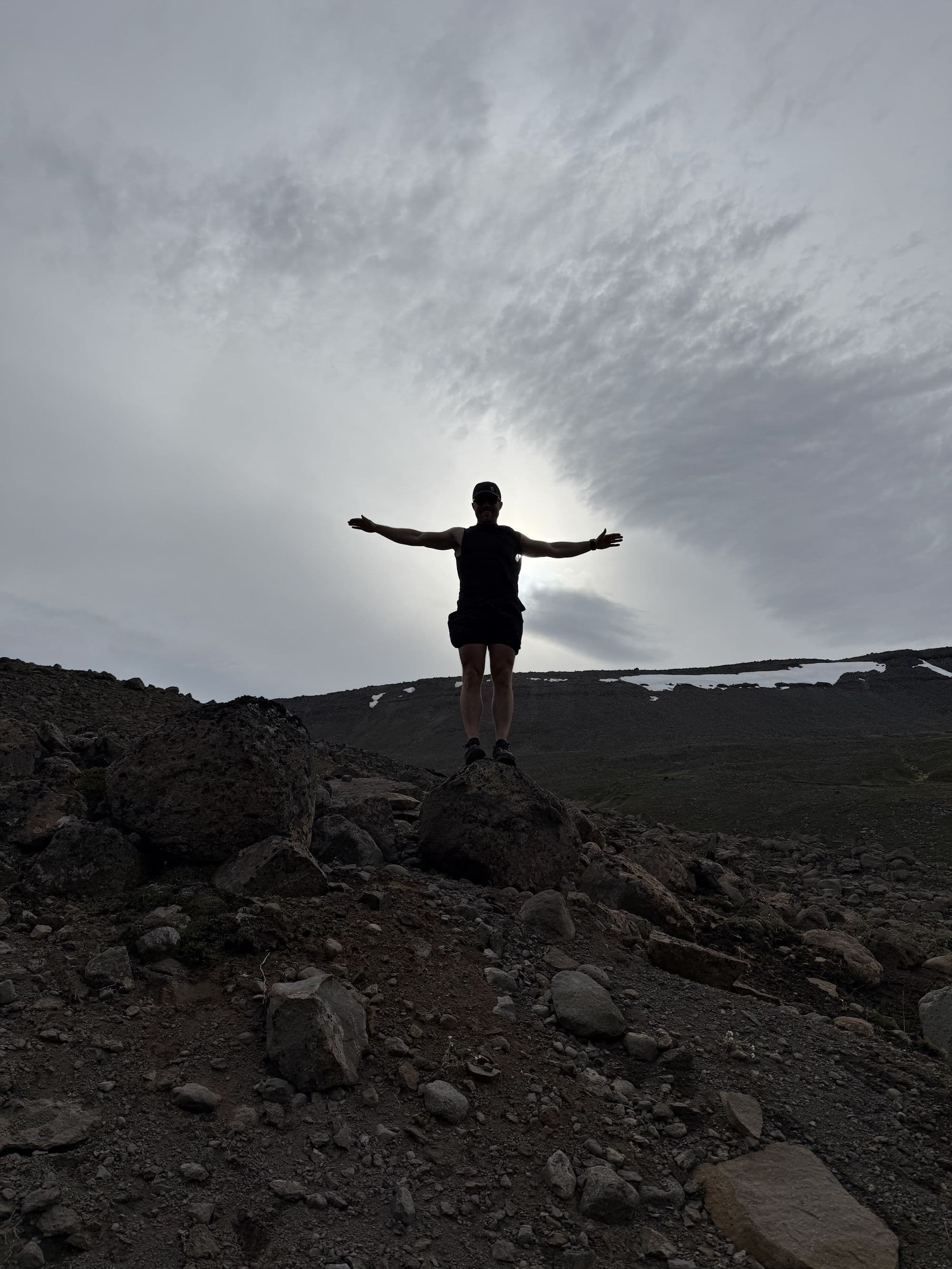 Justin, arms wide on a volcanic ridge