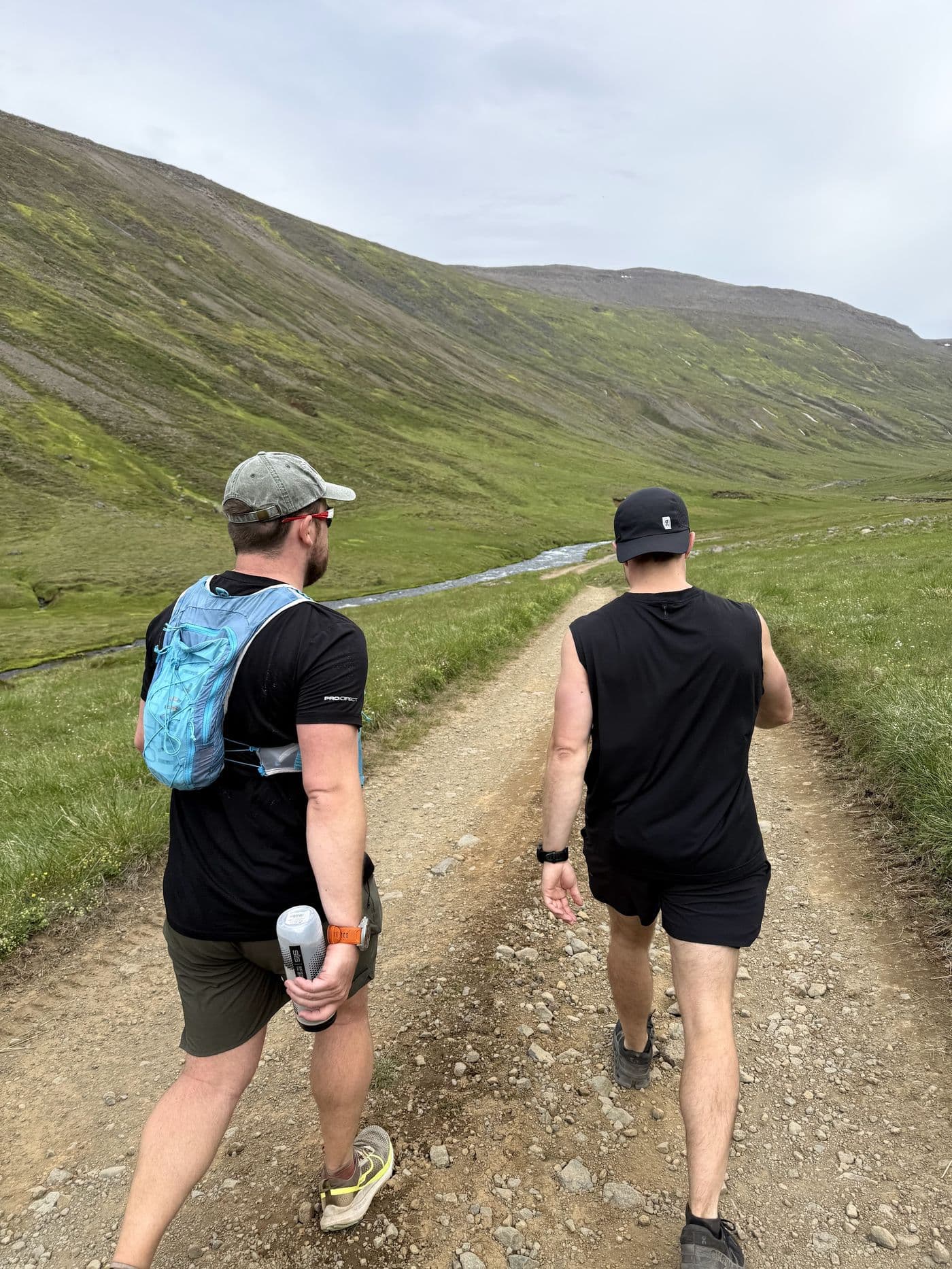 Two of the crew walking a green valley road between stages